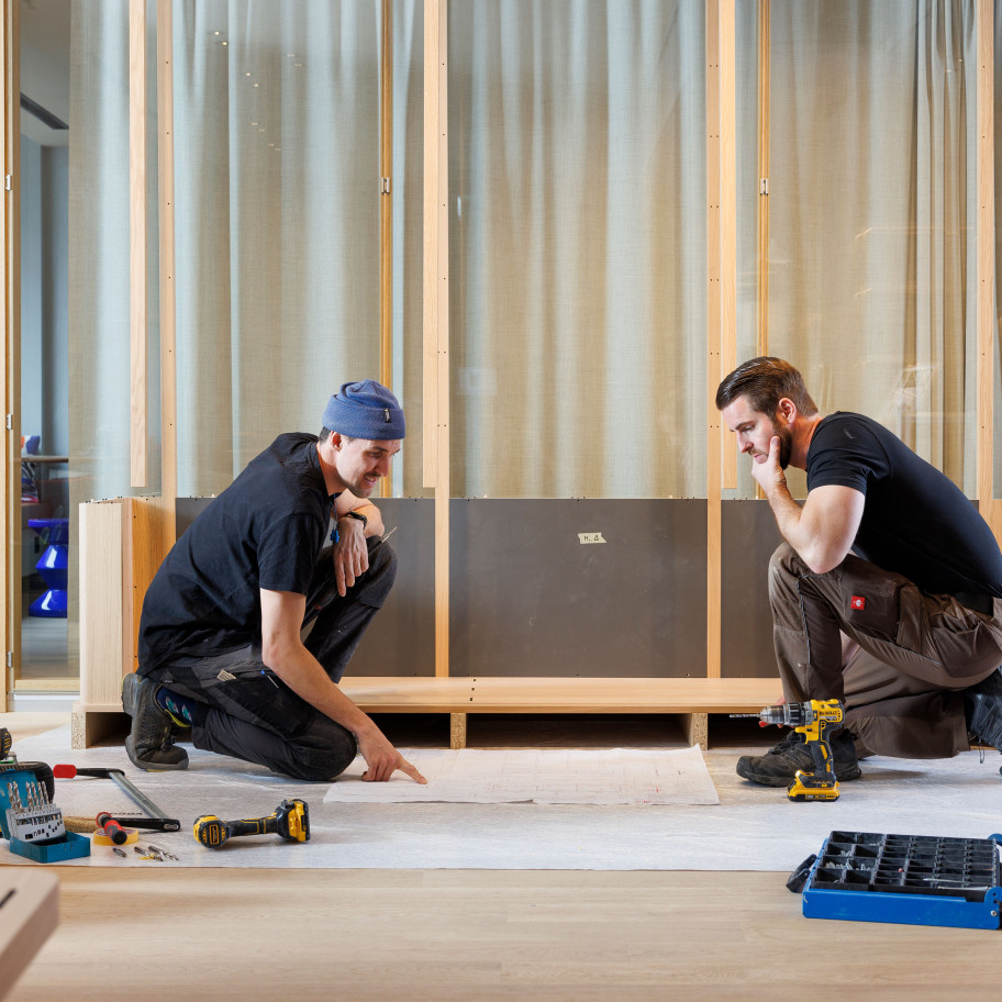 Zwei Handwerker bauen ein Regal in einer Hotellobby zusammen