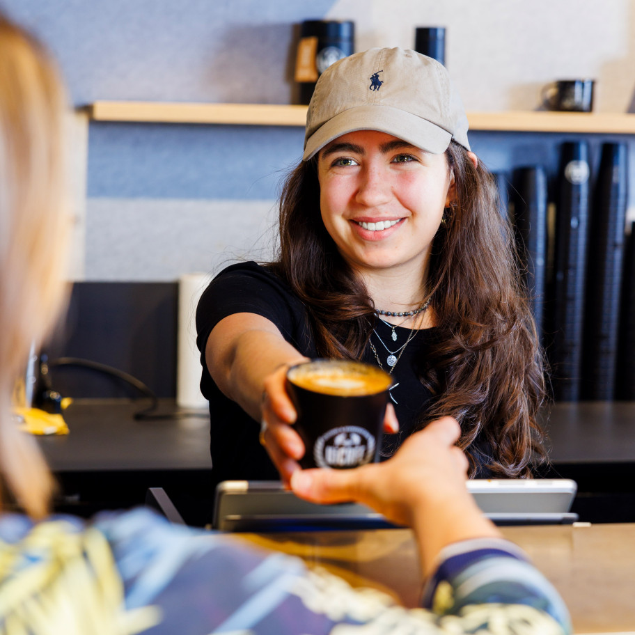 Junge Frau serviert einen Kaffee to go