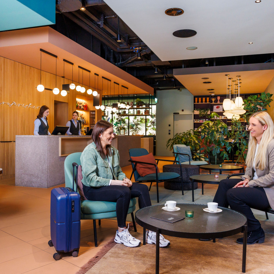 Zwei junge Frauen unterhalten sich in einer Hotellobby