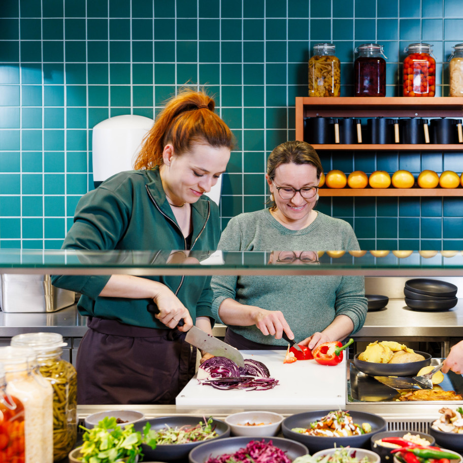 Drei Frauen stehen in der Gastroküche und kochen