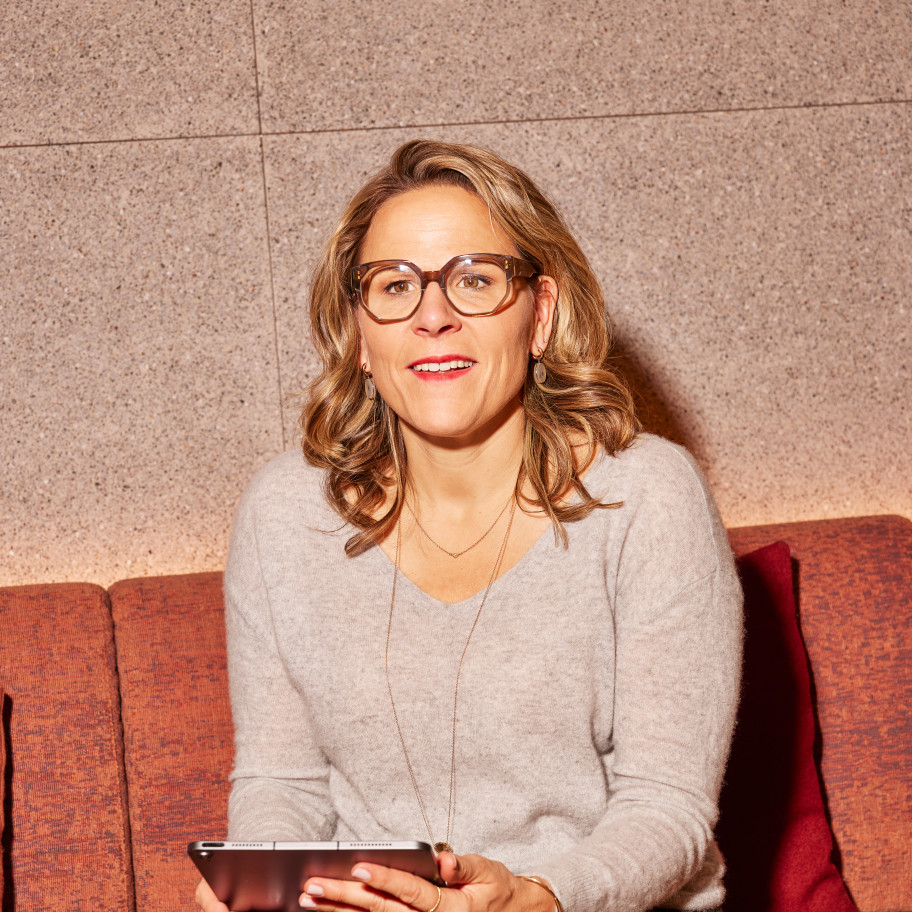 Frau sitzt auf einem Sofa und blickt in die Kamera