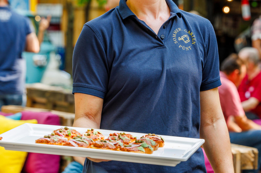 Servicefachangestellte serviert Fingerfood im Pünt Sommergarten