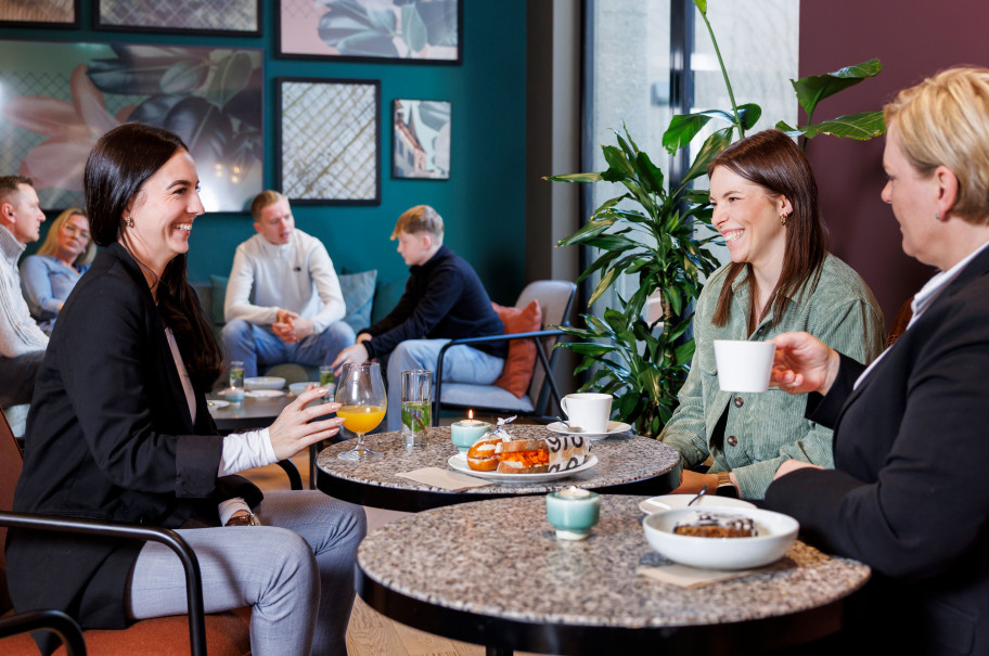 Mehrere Frauen sitzen an einem Tisch mit Kaffee vor ihnen und unterhalten sich