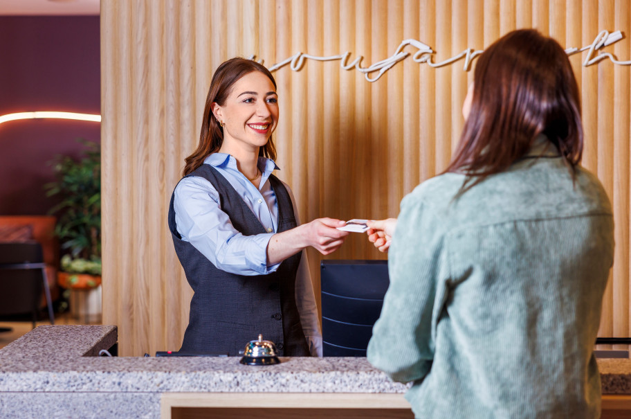 Junge Frau beim Check-in an einer Hotelrezeption