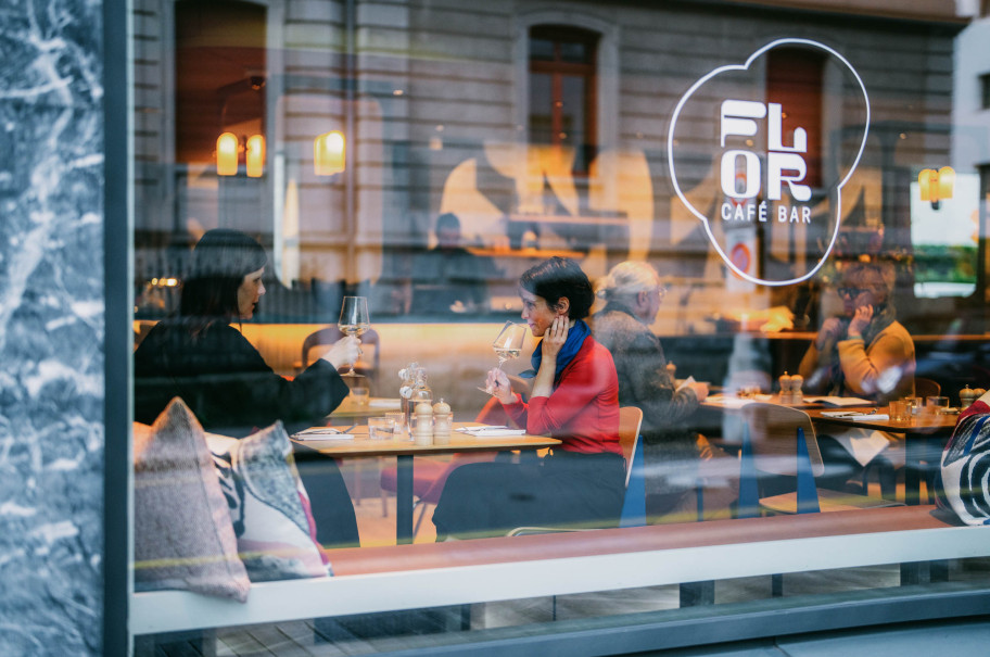 Glasfront eines Restaurants mit Logo, durch das Glas sind die Gäste im Restaurant zu sehen