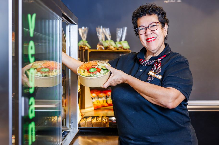Frau nimmt einen Salat zum Mitnehmen aus einer Kühlvitrine
