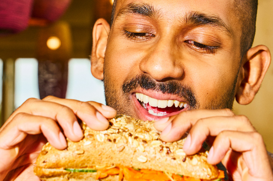 Mann beisst in ein Sandwich.