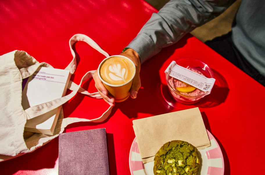 Roter Tisch auf dem eine Stofftasche und ein Cookie liegen.