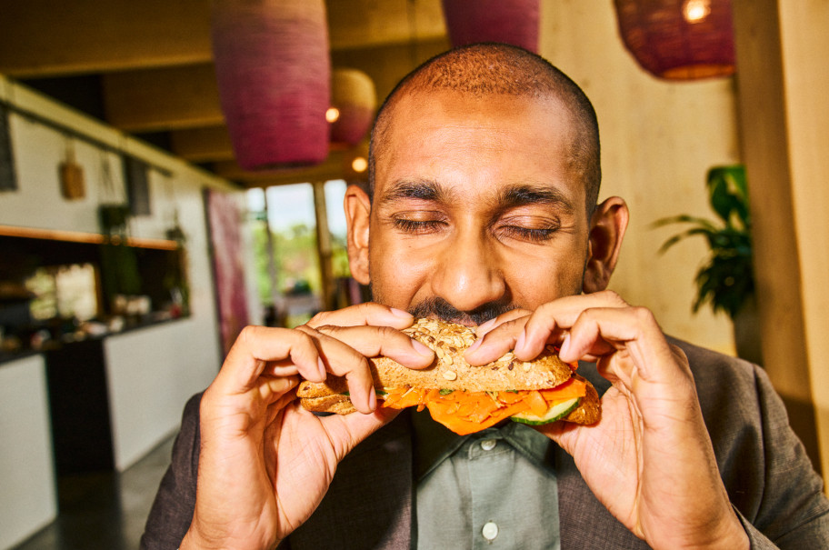 Mann beisst in eine Sandwich mit Gemüse