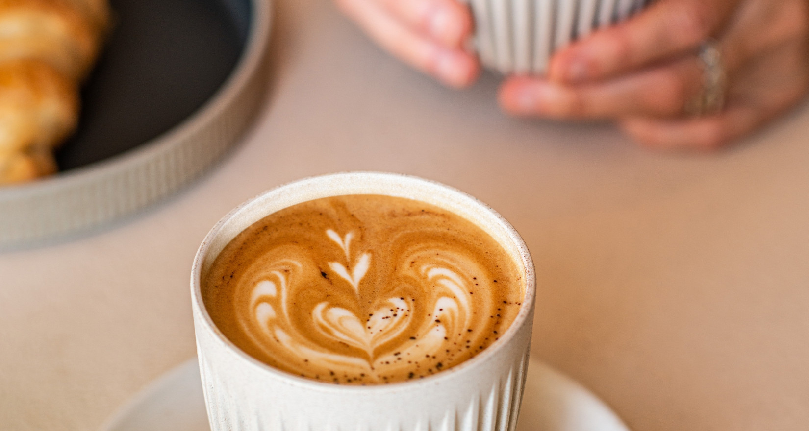 Kaffee auf einem Tisch und eine Kaffee-Tasse in der Hand