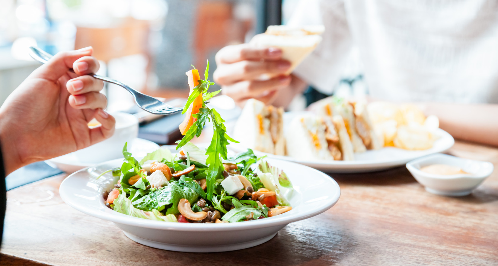 Businesslunch Sandwicht und Salat an einem Tisch mit hellem Tageslicht von rechts