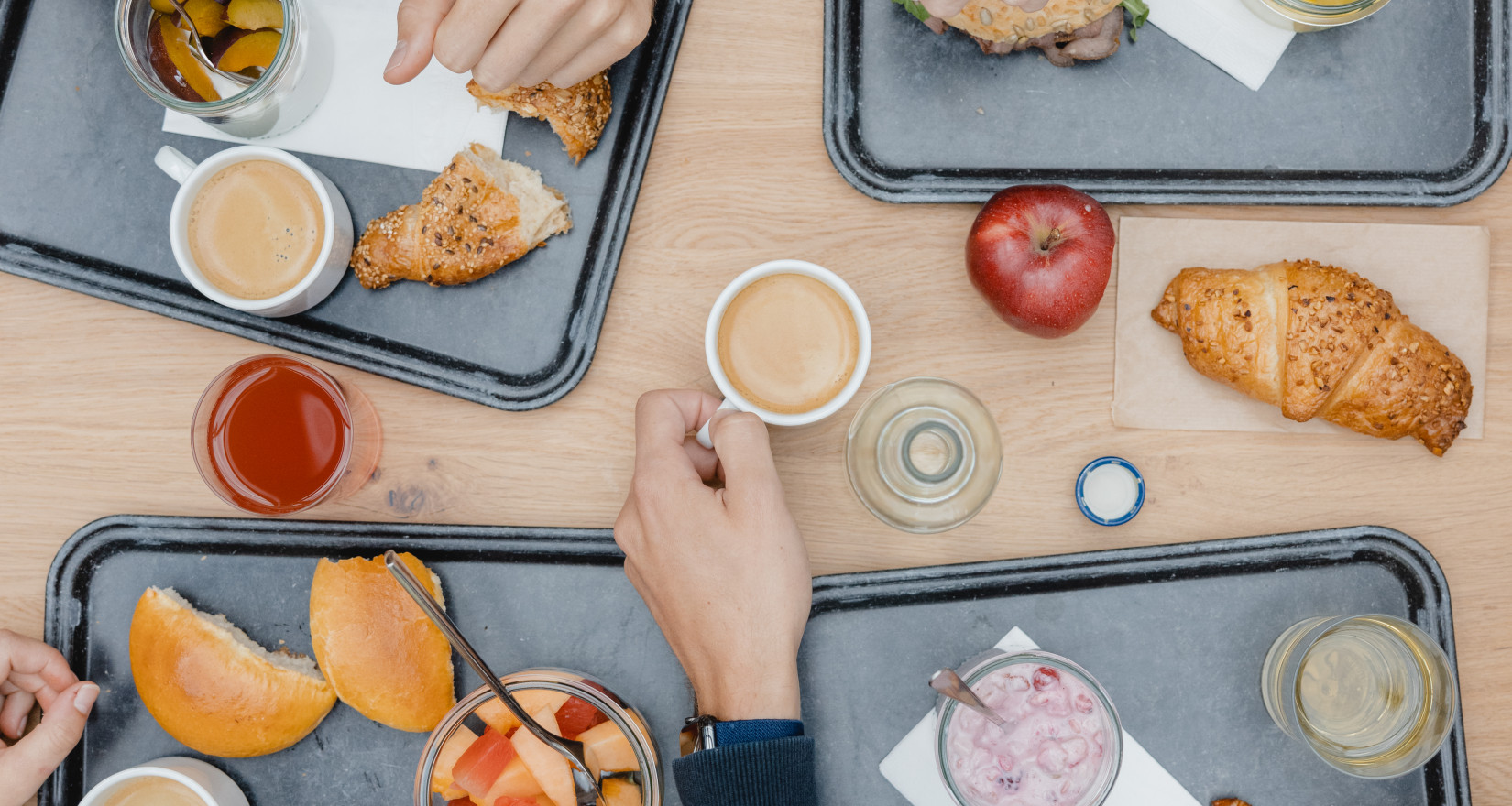vier Personen sitzen an einem Tisch und frühstücken Gipfeli und Müesli