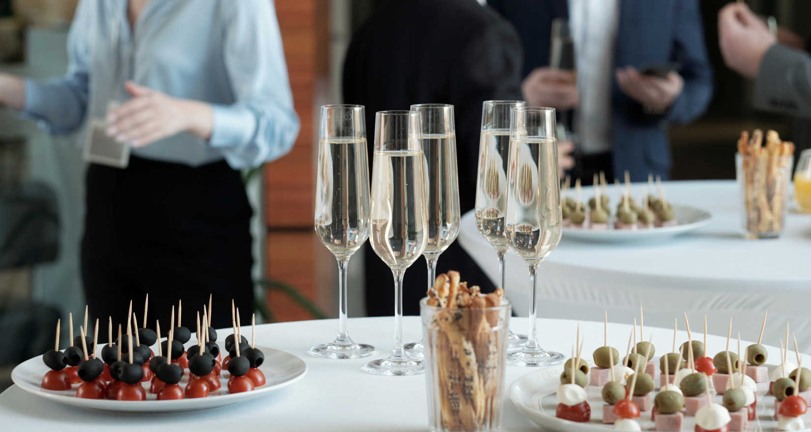 Aperohäppchen angerichtet auf weiss gedecktem Buffettisch mit Proseccogläsern