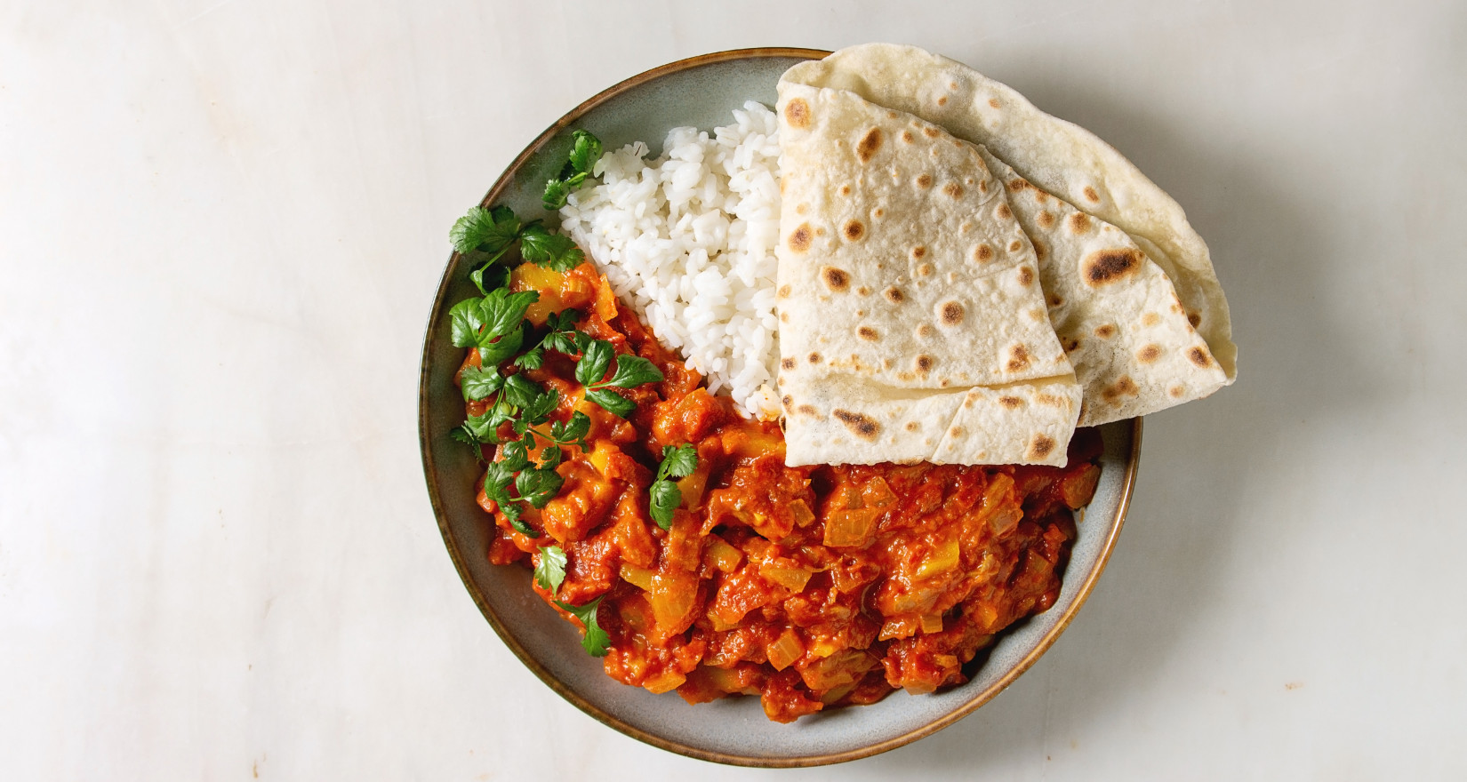 Jackfruit-Curry mit Reis, Fladenbrot und Koriander in einer Schüssel