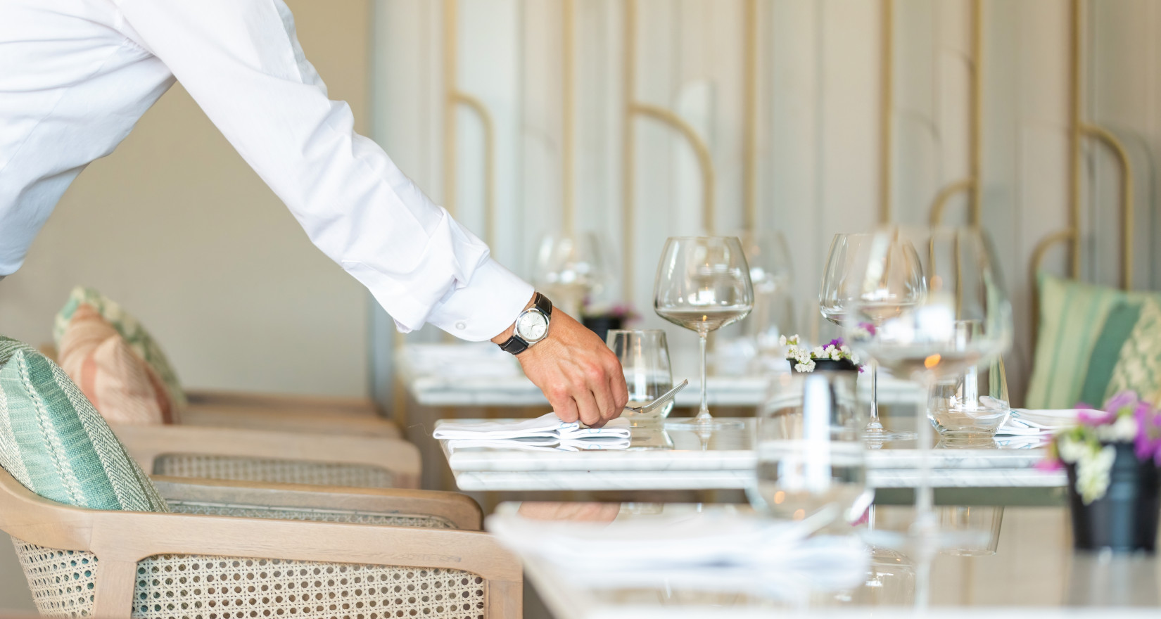 Tisch wird von einer männlichen Hand gedeckt im Restaurant