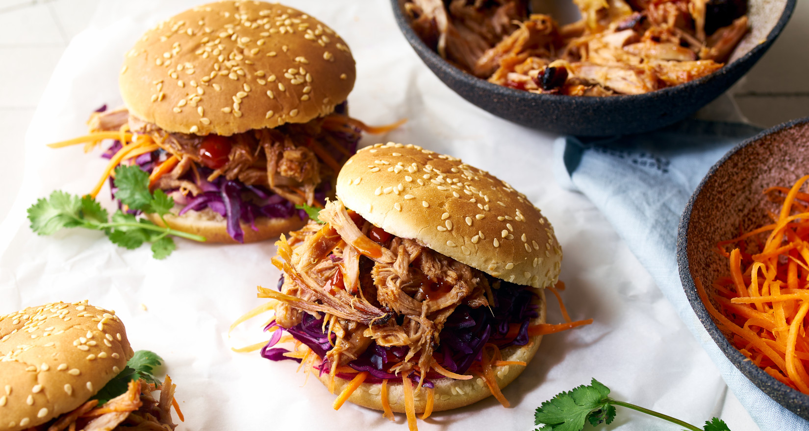 Drei Pulled Pork Burger mit Karotten, Rotkohl und Koriander