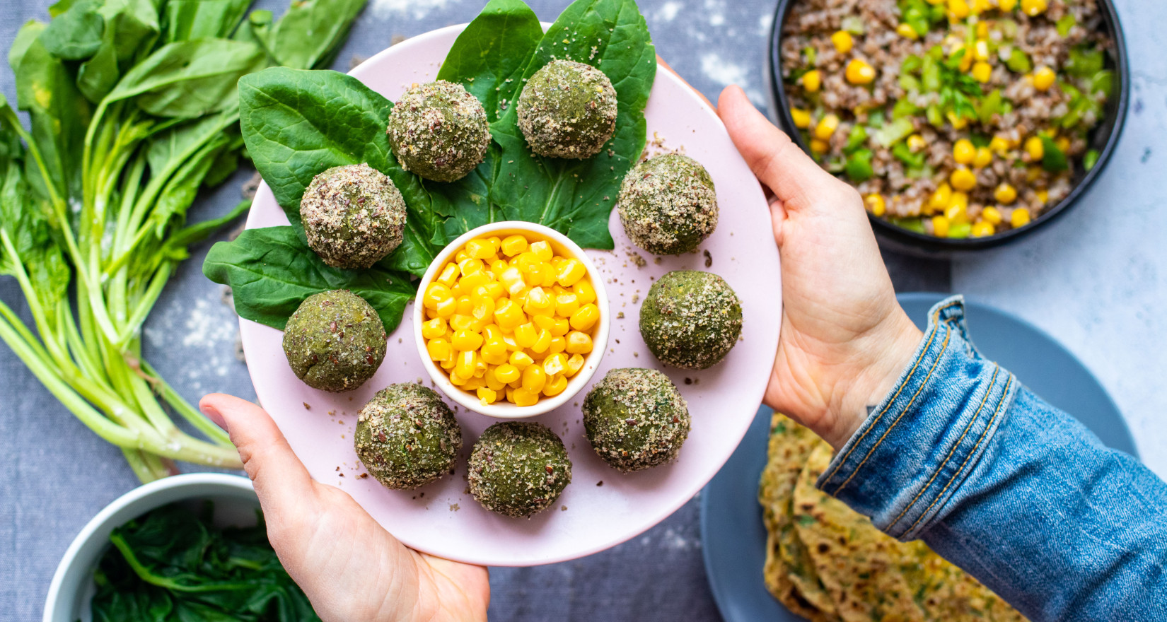 Bowl mit veganen grünen Falafel und Mais gehalten von Frauenhänden