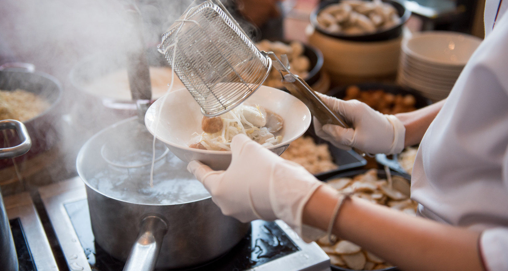 weibliche Hand schöpft thailändisches Essen aus einem grossen Topf