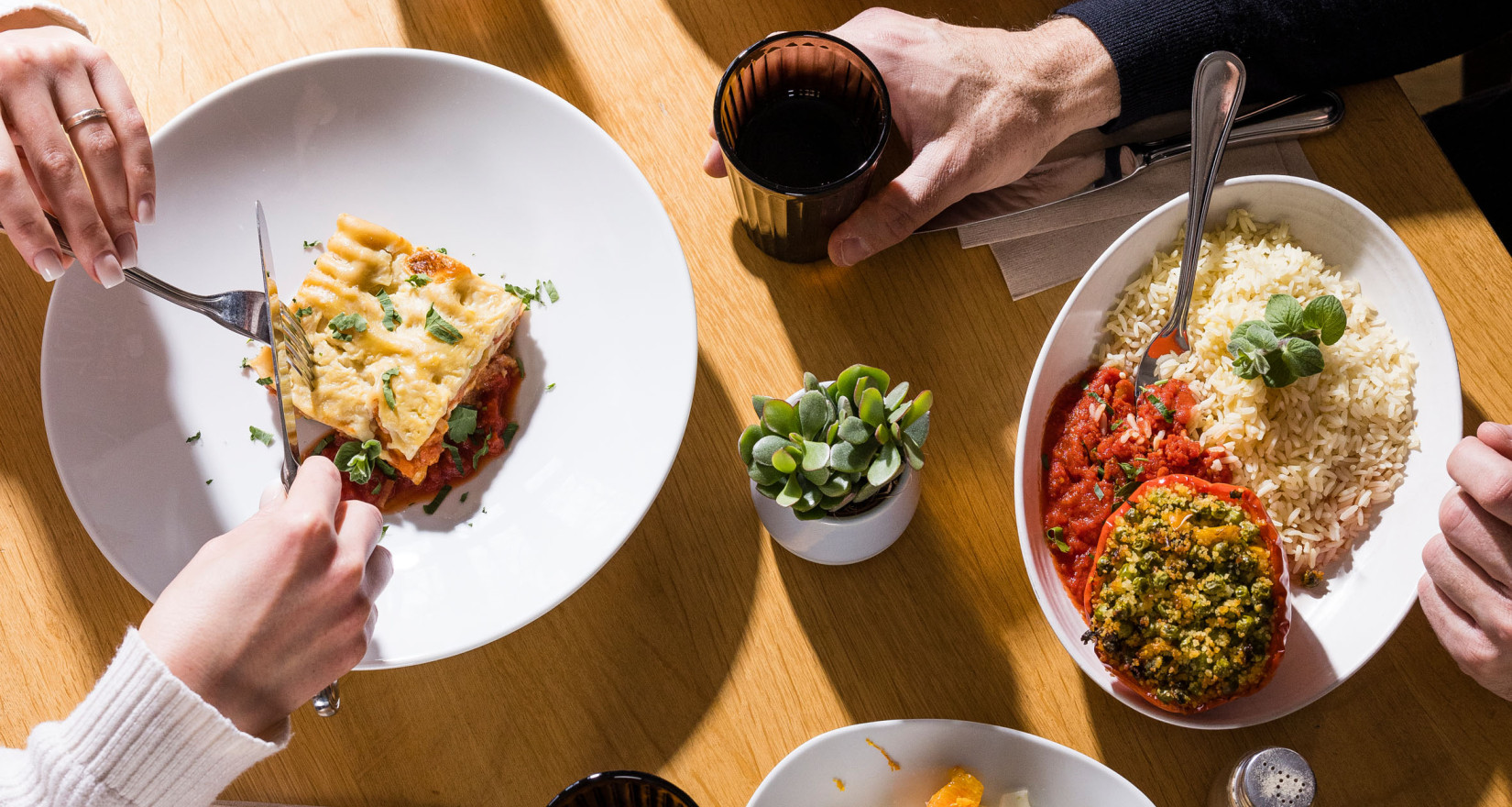 Tisch mit vier Gerichten und Menschen beim Essen