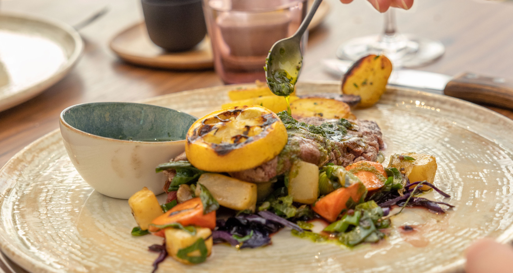 Teller mit weiblichen Händen, die Sauce auf ein Fleischgericht träufeln