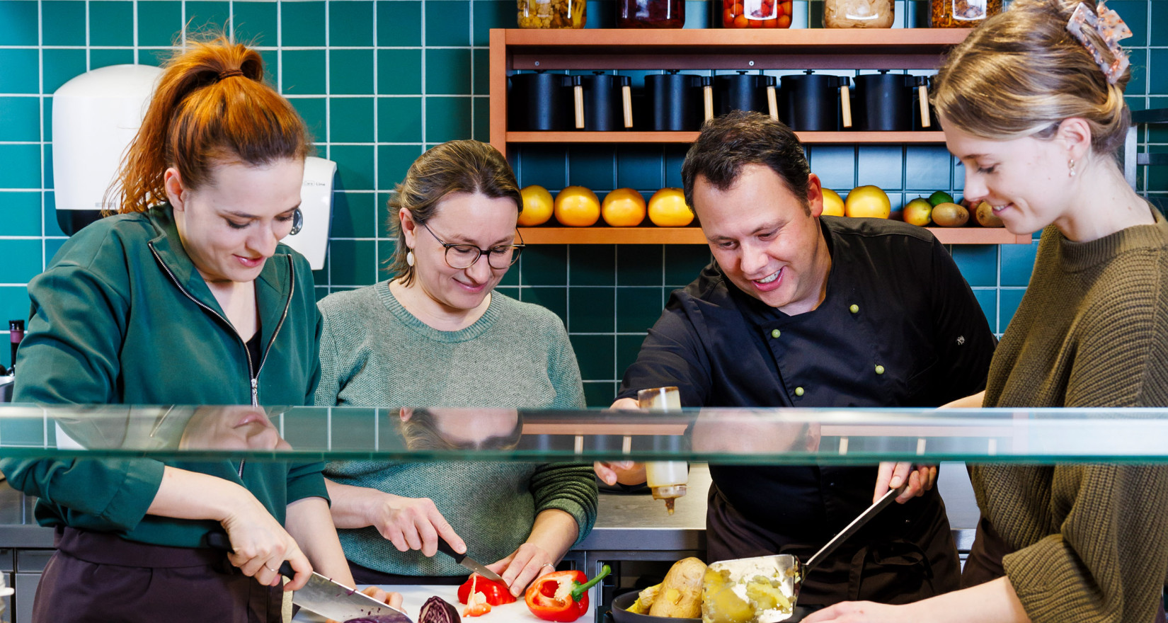 Team in einer Küche bereitet gemeinsam Essen zu