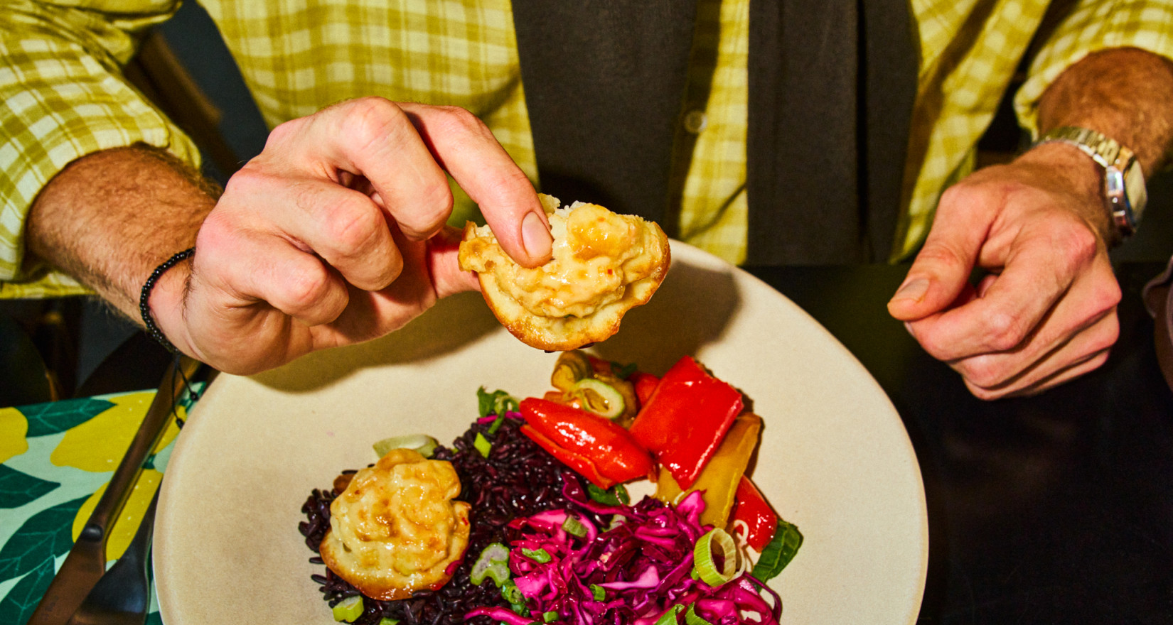 Teller mit Essen, männliche Hand hebt ein Stück hoch