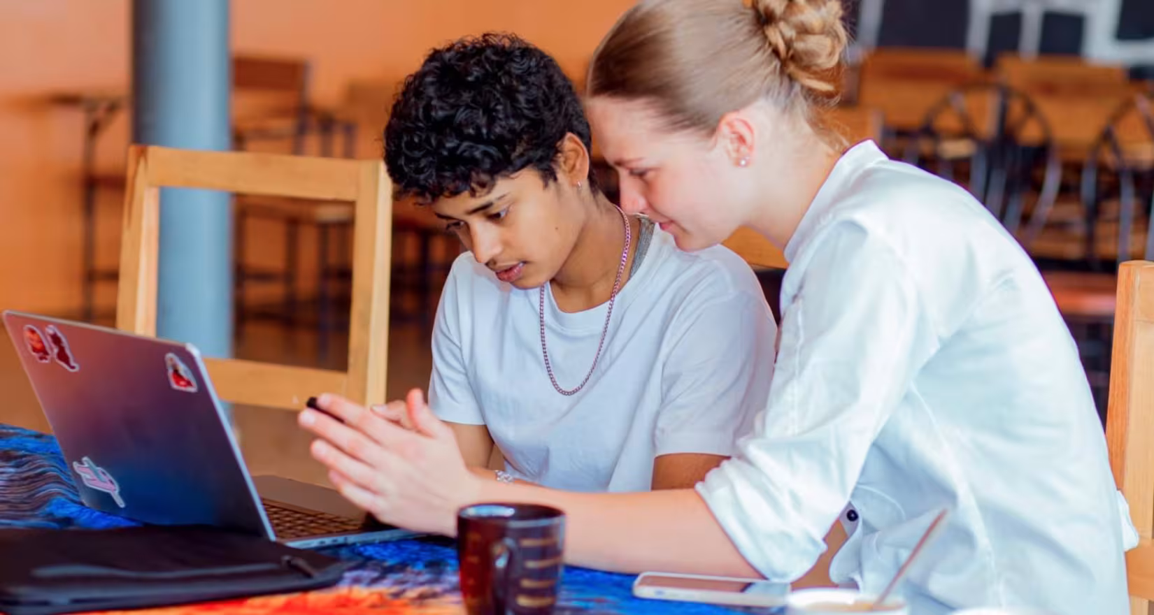 Zwei junge Frauen arbeiten gemeinsam an einem Laptop