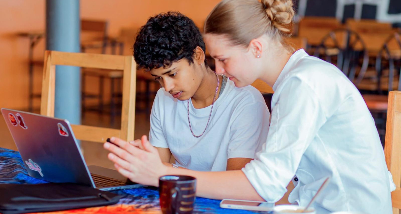 Zwei junge Frauen arbeiten gemeinsam an einem Laptop