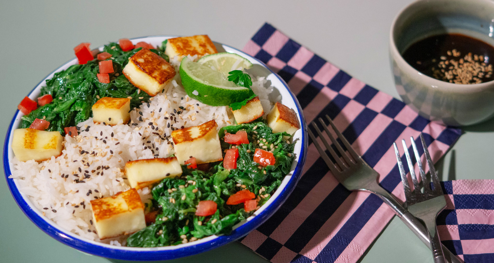 Teller mit Reisgericht und Spinat angerichtet auf einem Tisch