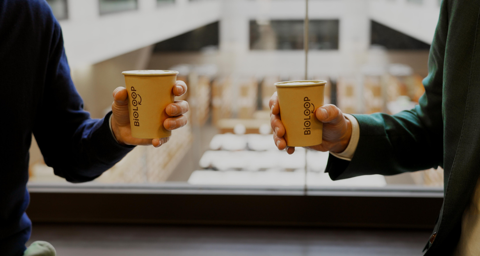 Zwei Männerhände halten Einweg-Kaffeebechern 