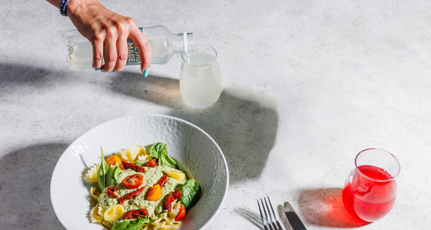 Teller mit Pasta und Hand, die etwas eingiesst