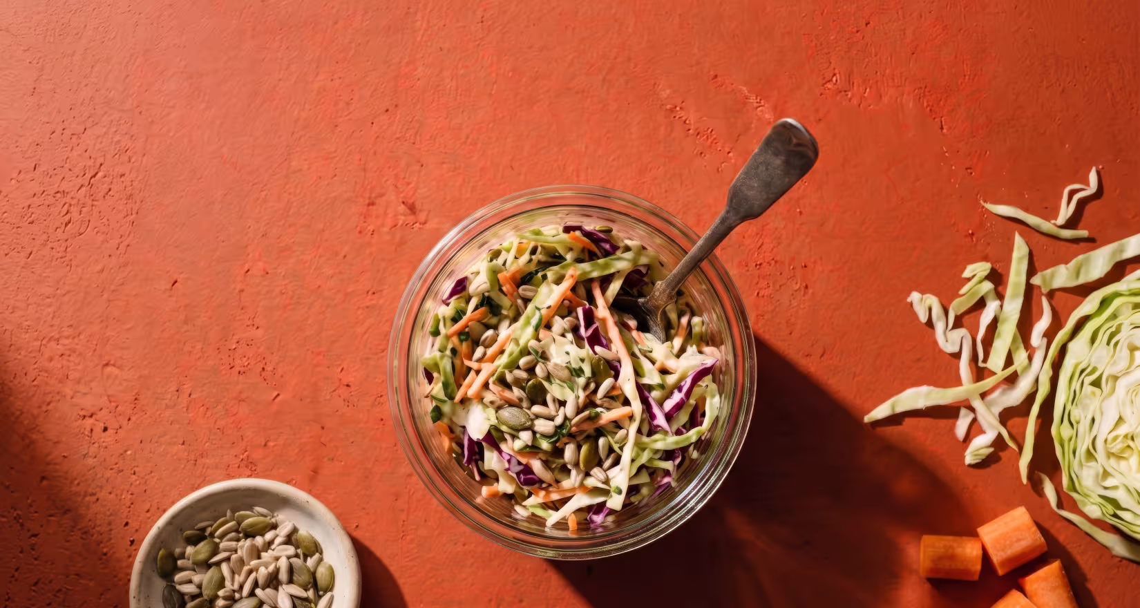 Weckglas mit Coleslaw, daneben liegen Kohl und Karotten