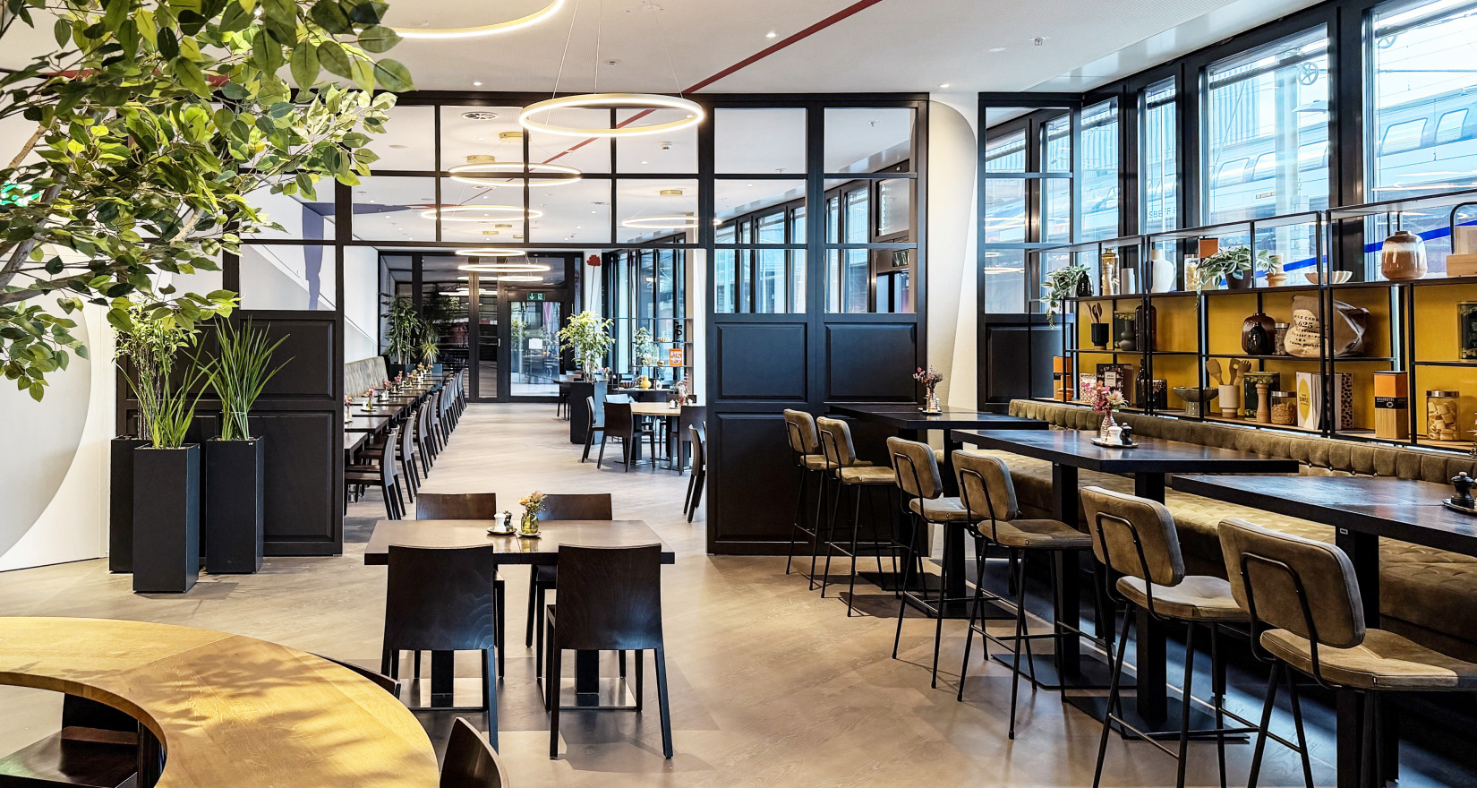 Moderner Restaurantbereich der EY Platform Zürich mit Holztischen, Sitzgelegenheiten und grossen Fensterfronten.