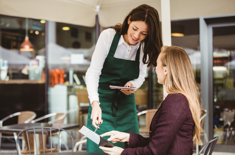 Restaurantsituation Kellnerin kassiert eine Dame ein