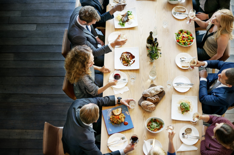 Personen an einem langen Tisch beim Mittagessen