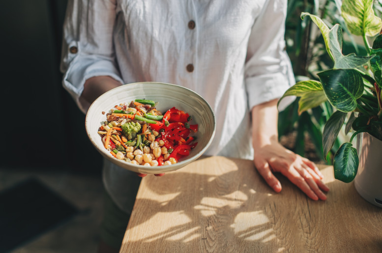 Person hält Bowl mit Gemüse in der Hand