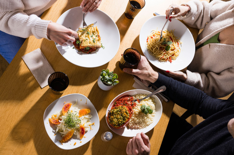 Tischszene mit mehreren Menschen beim Essen aus der Vogelperspektive