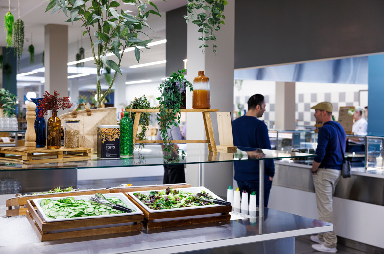 Zwei Männer hinter einem Buffet mit frischem Salat an der Essensausgabe