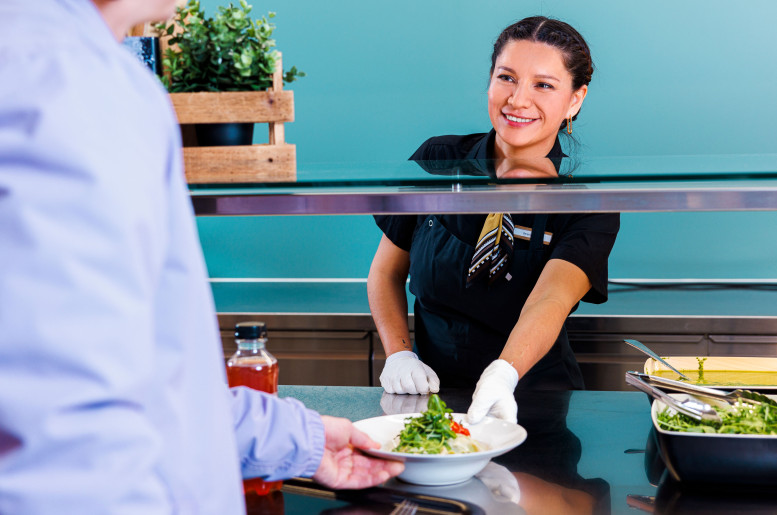 Frau gibt einen Teller Pasta in einem Personalrestaurant aus