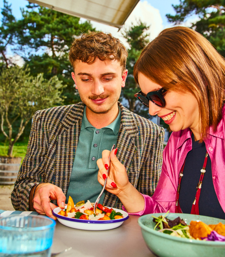 Frau und Mann sitzen in der Sonne und essen ihr Mittagessen.