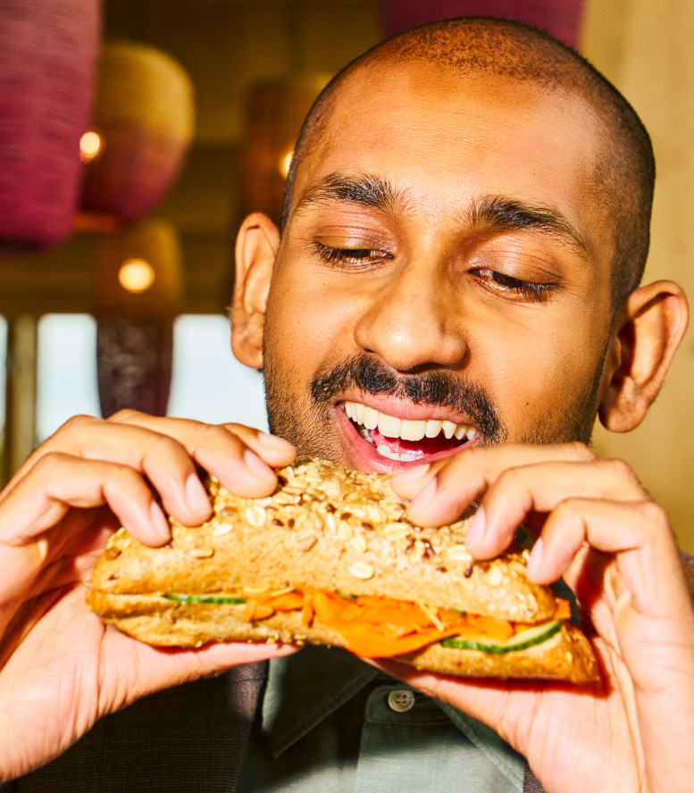 Mann beisst in ein Sandwich.