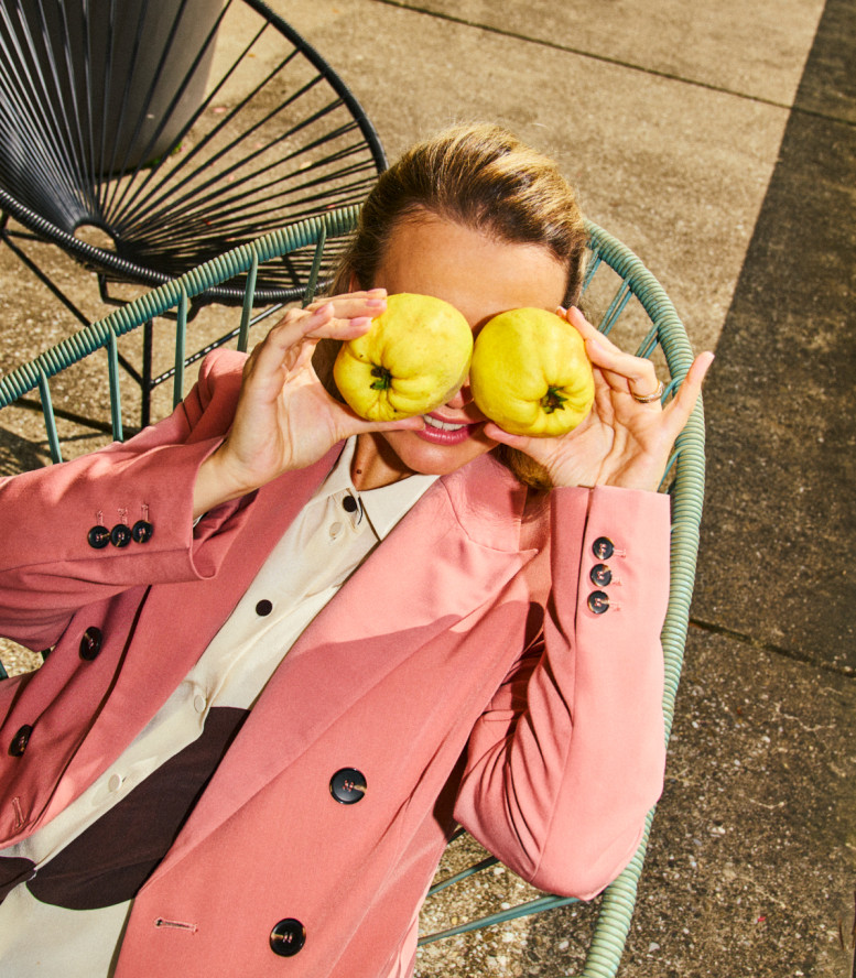 Frau sitzt im Stuhl und hält sich zwei Äpfel über die Augen.