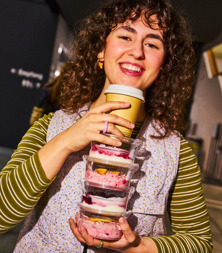 Eine junge Frau hält einen Turm aus Birchermüesli-Boxen.