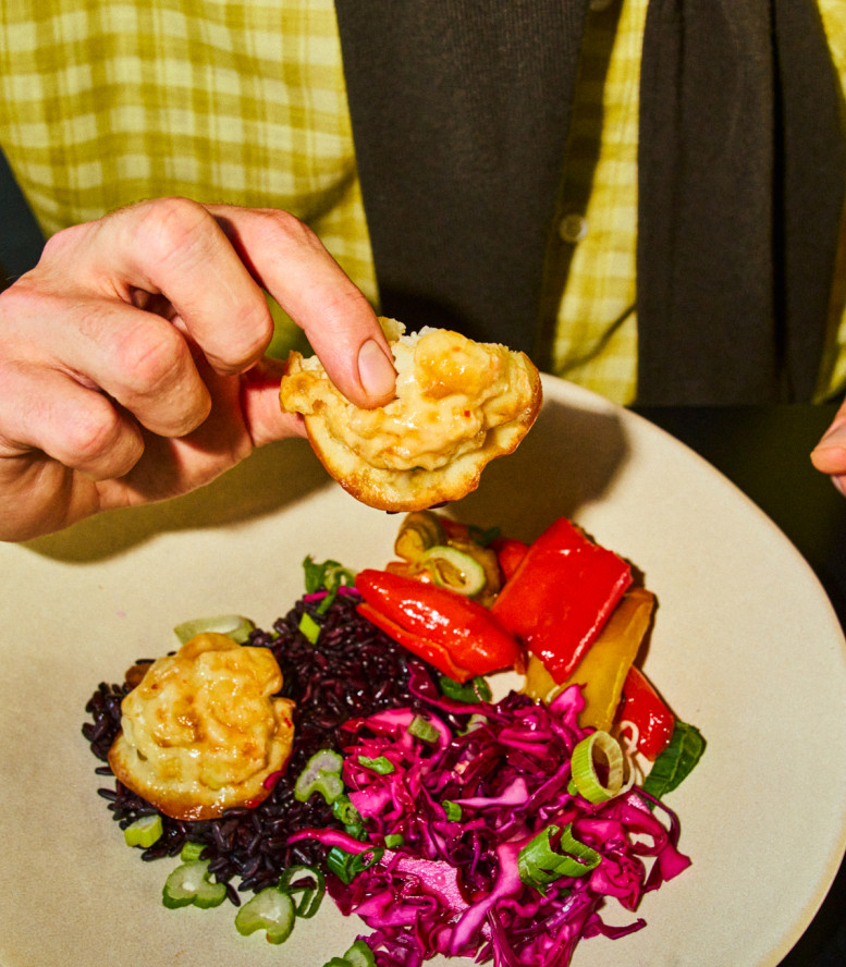Teller mit Essen, männliche Hand hebt ein Stück hoch