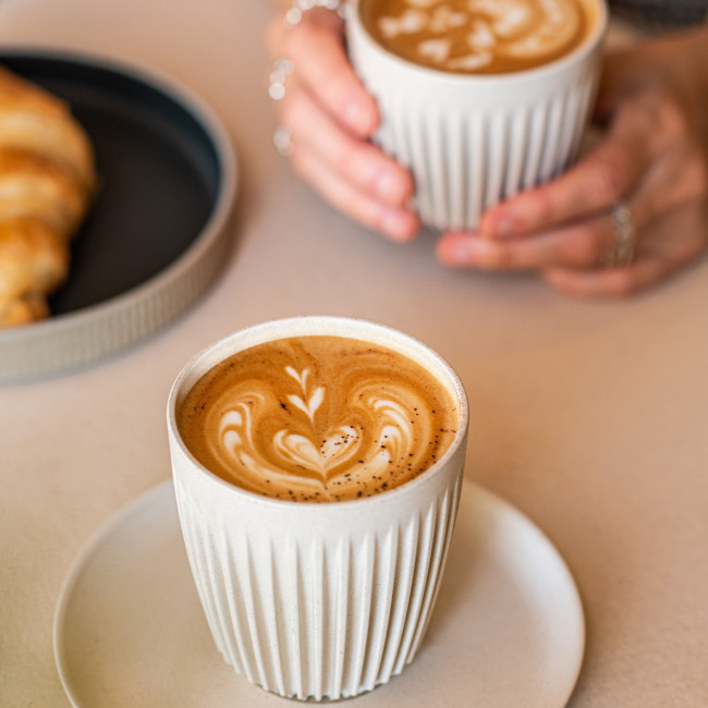 Kaffee auf einem Tisch und eine Kaffee-Tasse in der Hand