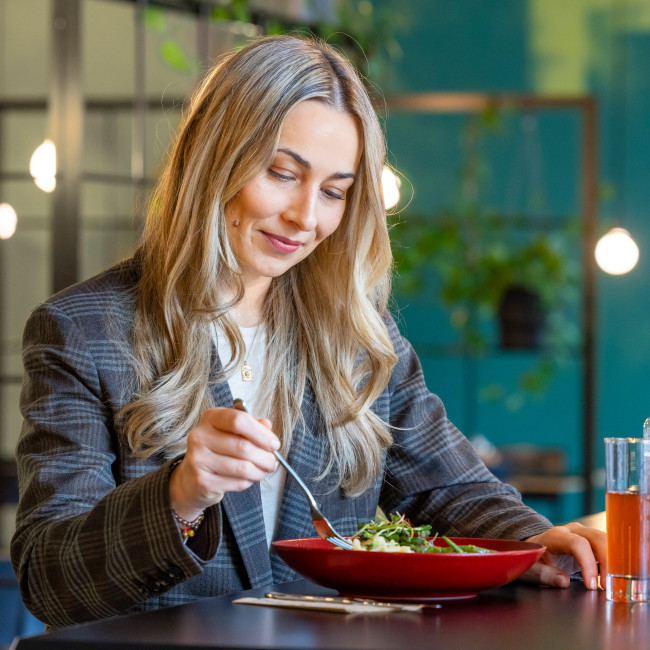 blond women eating a salad in a bowl