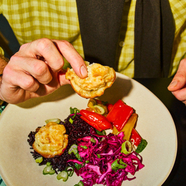 Teller mit Essen, männliche Hand hebt ein Stück hoch