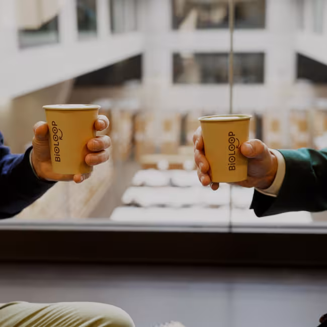 Zwei Männerhände halten Einweg-Kaffeebechern 