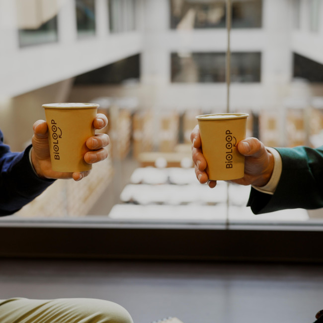 Zwei Männerhände halten Einweg-Kaffeebechern 