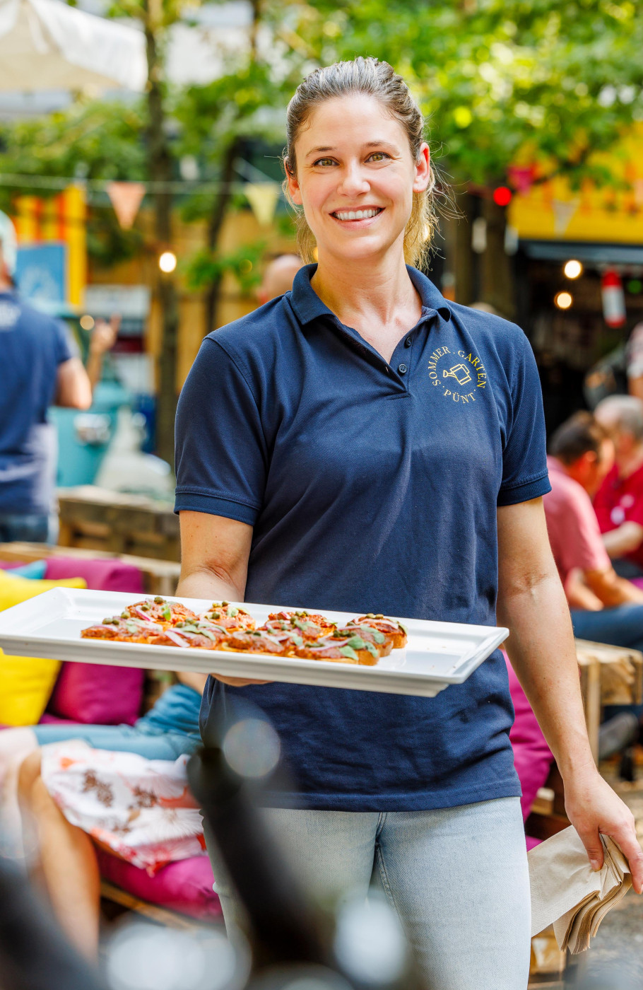 Servicefachangestellte serviert Fingerfood im Pünt Sommergarten